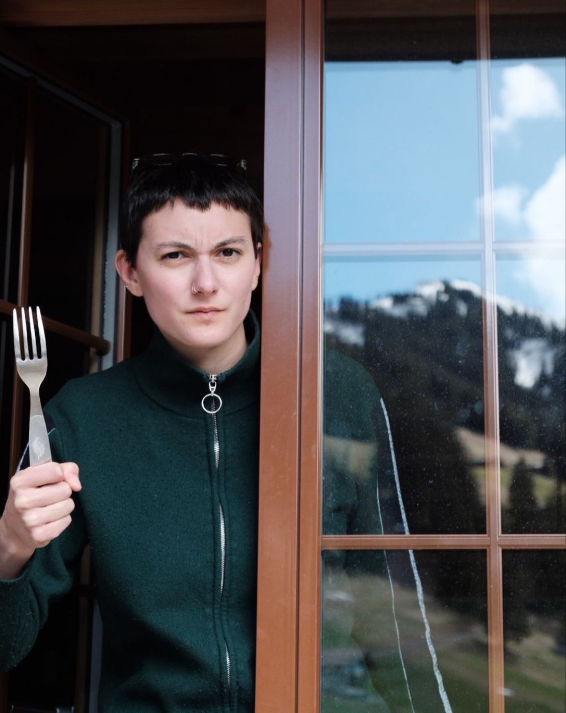 Portraitfoto von Nina Hurni. Sie steht mit einer Gabel in der Hand am Fenster und schaut ein wenig böse aus.
